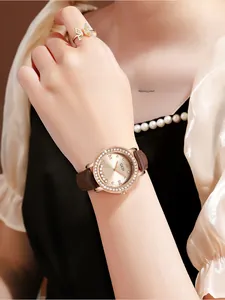 Détails d'une montre en or rose avec strass mobiles et bracelet en cuir marron