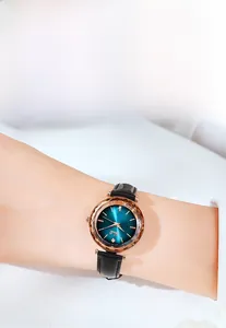 Détail d'une montre en or rose avec verre facetté polygonal, cadran bleu et bracelet cuir