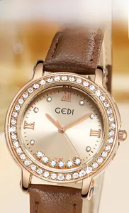 Détail de la montre en or rose sertie de strass avec un bracelet en cuir marron