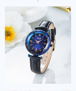 Gros plan d'une montre à cadran bleu soleil avec verre facetté et bracelet cuir noir