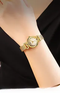 Détail d'une montre à quartz dorée pour femme avec bracelet en maille au poignet