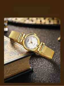 Gros plan d'une montre femme GEDI dorée avec cadran texturé sur un livre ancien