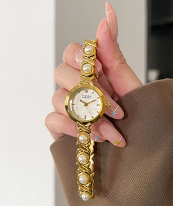 Detail of luxury gold quartz watch with elegant pearl bracelet and minimalist dial
