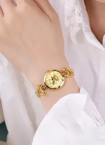Détail du bracelet de montre doré à maillons en forme de cœur sur un poignet