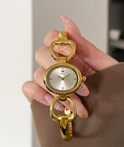 Close-up of golden oval dial ladies watch with horseshoe-shaped bracelet band