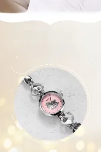 Détail du cadran rose avec motif licorne et chaîne en argent en forme de cœur sur montre