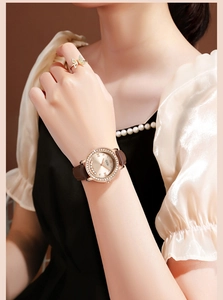 Détail d'une montre de luxe en or rose avec strass brillants et bracelet en cuir marron