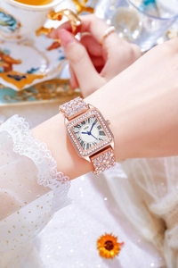 Close-up of luxury rose gold square watch with crystal-encrusted bezel and ROMAN dial