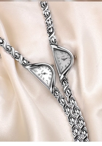 Macro view of silver vintage quartz watch featuring a unique triangular dial on silk