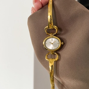 Detailed macro view of the oval dial and gold-tone bangle bracelet strap on this lady watch