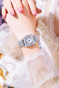 Close-up of luxury square watch with sparkling rhinestones and blue hands on female wrist