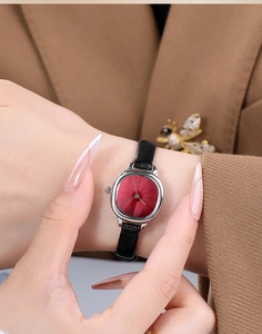 Macro shot of woman wearing a small square watch with red sunburst dial and black leather strap
