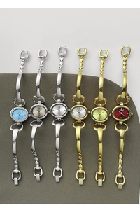 Detail view of oval minimalist bracelet watches with various color dials on fabric