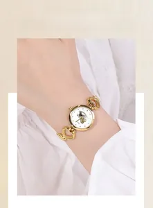 Détail de la montre bracelet à maillons en cœur dorés avec cadran licorne sur un poignet
