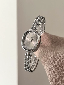 Close-up of elegant oval women's watch with silver sunray dial and Roman numerals