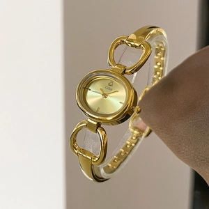 Detail of GEDI gold oval watch featuring heart-shaped bracelet links and sunray dial design