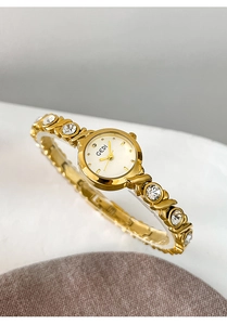 Detailed close-up of a luxury gold GEDI watch band with embedded rhinestones and white dial