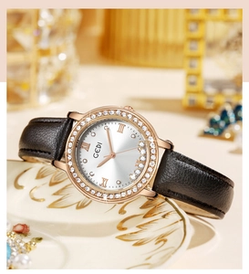 Gros plan d'une montre en or rose avec lunette en strass et bracelet en cuir noir sur porcelaine