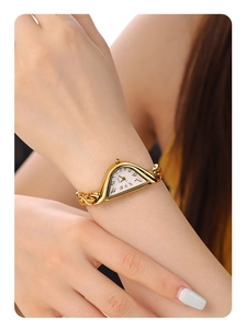 Macro shot of gold-tone chain link bracelet and triangle dial on luxury quartz watch