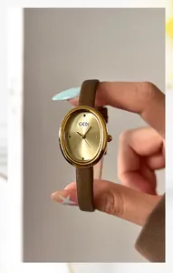 Detailed view of an oval gold quartz watch with a brown leather strap and brushed dial