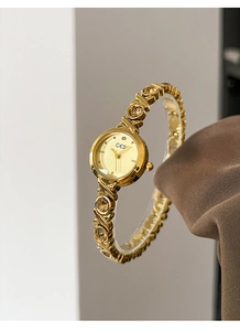 Close-up of gold-plated alloy ladies' quartz watch with crystal accents and X-pattern band