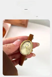 Close-up of vintage oval gold watch with champagne dial and brown leather strap