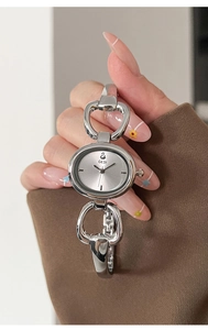 Close-up of GEDI oval silver bangle watch with jewelry links on woman wrist