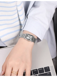 Close-up of a square silver quartz watch for women worn while typing on a laptop