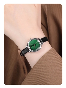 Close-up of vintage women quartz watch with emerald green dial and black leather strap