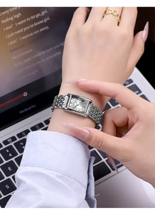Elegant rectangular silver watch with metal chain strap on a wrist in a lifestyle setting