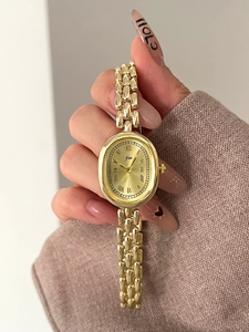 Detail of elegant gold oval watch with Roman numeral dial on a metal chain strap