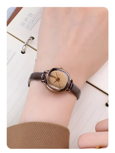 Close-up of minimalist square gold watch with brown leather strap on female wrist