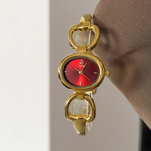 Detailed macro view of an oval red dial ladies watch with a gold chain bracelet