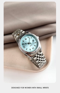 Détail de montre à quartz argentée avec cadran bleu clair et lunette cannelée sur un plateau