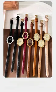 Overhead view of minimalist oval quartz watches with diverse leather straps on a warm mat
