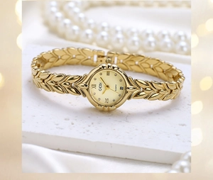 Macro detail of gold wheat ear strap watch with crystal markers and date display