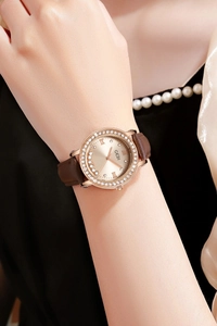 Détails d'une montre en or rose avec strass et bracelet en cuir marron sur fond élégant