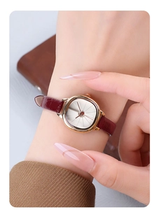Close-up of a vintage rose gold square watch with brown leather strap on a model's wrist