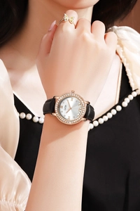 Gros plan d'une montre GEDI pour femme avec strass, bracelet cuir et bague papillon dorée