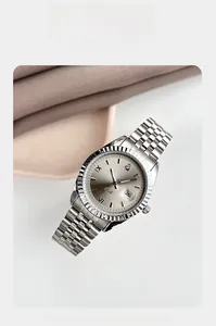 Détail macro d'une montre en acier argenté avec lunette cannelée et guichet de date intégré