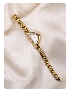 Macro detail of GEDI gold luxury watch with a half-moon dial on silk fabric