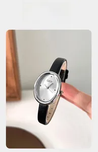 Close-up of GEDI oval silver watch with sunray dial and black leather strap held in hand
