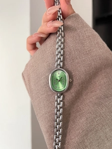 Detailed macro view of the oval green dial and silver beaded bracelet watch for women