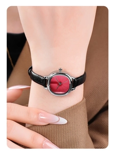Detail shot of a vintage small red dial watch with black leather strap on a wrist