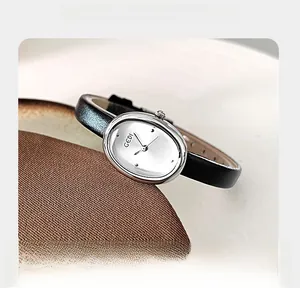 Detailed view of an oval silver quartz watch with a black leather strap and textured dial