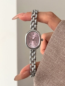 Close-up of elegant oval watch with pink sunray dial and silver chain bracelet