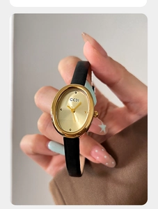 Macro detail of retro oval gold quartz watch with a black leather strap on a wrist