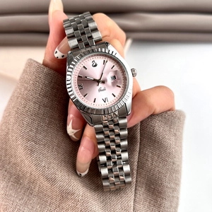 Détail d'une montre à quartz pour femme avec cadran rose et lunette cannelée argentée