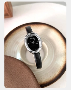 Detail of elegant oval black dial watch with silver case and black leather strap