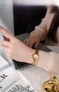 Elegante orologio a catena dorata sul polso femminile in un caldo ambiente di ufficio